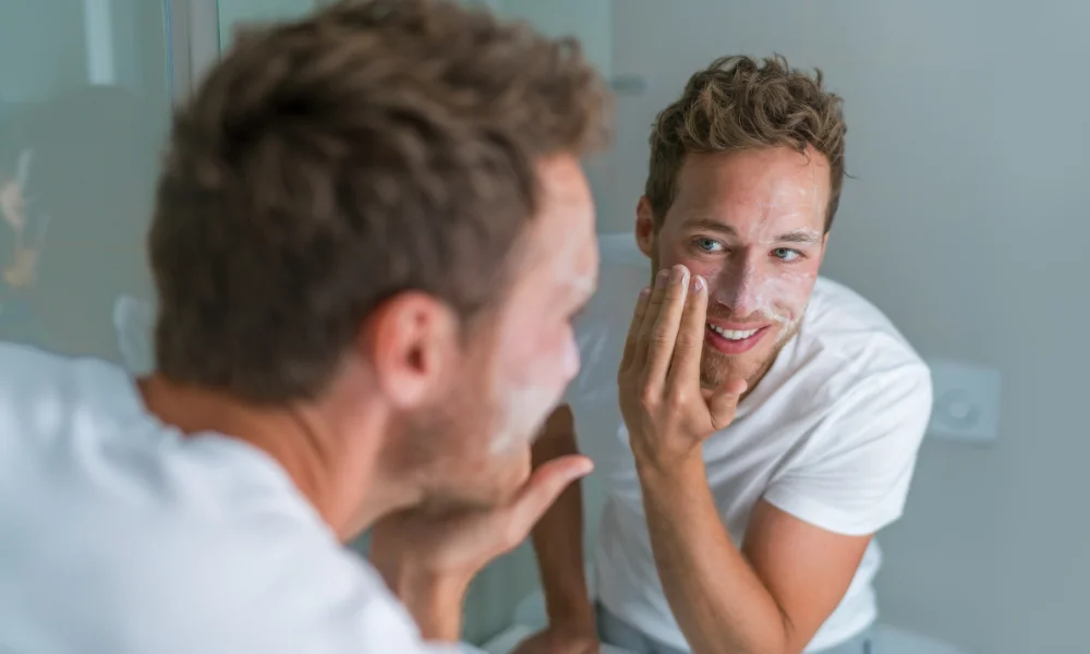young-man-using-face-cleanser-face-wash-mirror-1000x600